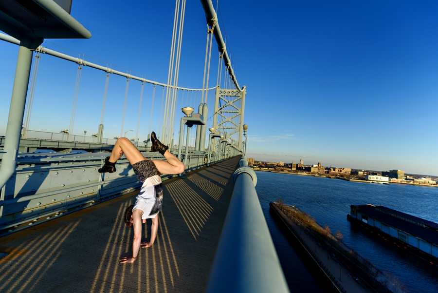 A woman doing a handstand on the ben franklin bridge in Philadelphia.